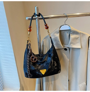 Detail of black marble textured underarm bag with amber beads and a brown knot charm