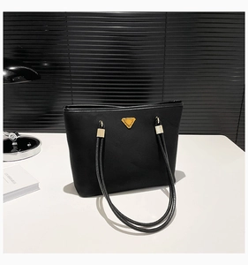 Detail of black nylon tote bag with golden triangle logo and stylish rope shoulder straps