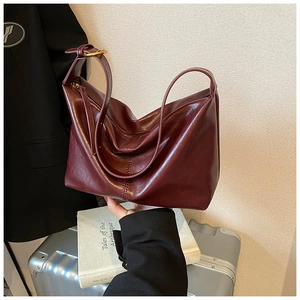 Detail of burgundy faux leather hobo bag with smooth texture and golden metal buckle