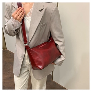 Detail of vintage dark red leather crossbody bag worn with a tailored grey blazer