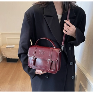 British style wine red satchel bag with retro flap design and top handle on a model
