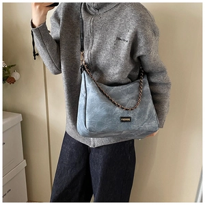 Detail of grey-blue crossbody bag with washed wrinkle texture and metallic chain link