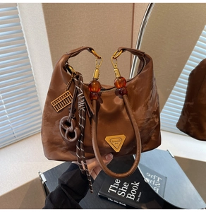 Close-up of a brown nylon hobo bag with red beaded handle and golden triangle logo plaque