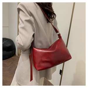Detail view of burgundy vintage pillow bag with smooth faux leather texture and adjustable strap
