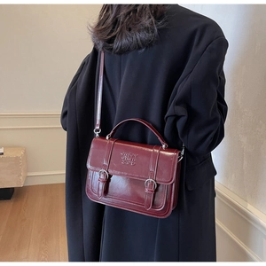 Close-up of wine red vintage handbag featuring shiny leather finish and silver buckles