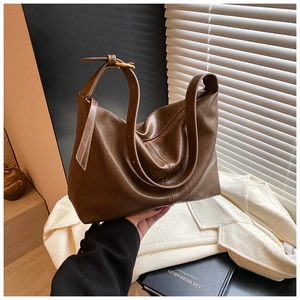 Detail of a brown leather hobo bag with adjustable strap buckle and soft matte texture