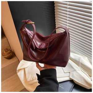 Macro detail of wine red leather tote bag with elegant gold adjustable buckle and zipper