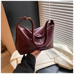 Close-up of burgundy leather hobo bag featuring adjustable golden strap buckle and seam detail
