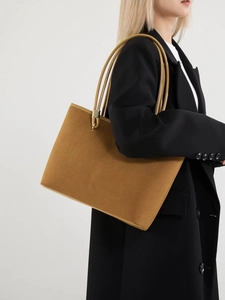 Large tan suede tote bag with slim shoulder straps worn by model for daily commute
