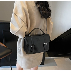 Detail of glossy black vintage satchel with embossed letters and metal buckles