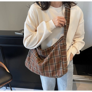 Detail of adjustable metal buckle and blue-brown checkered canvas tote on model