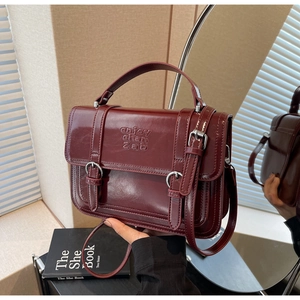 Close-up of wine red textured handbag showing mirror reflection and embossed details