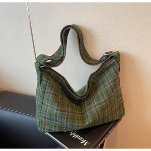 Detail of green plaid tote bag fabric with silver buckle and soft strap texture