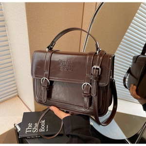 Detail view of dark brown vintage handbag with leather texture and engraved branding