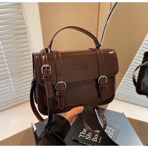 Close-up of brown vintage leather handbag showing silver hardware and engraved details