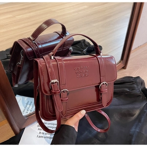 Macro detail of burgundy retro leather handbag with dual buckle and embossed texture