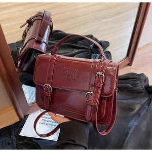 Macro view of burgundy retro leather handbag showing buckle details and embossed texture