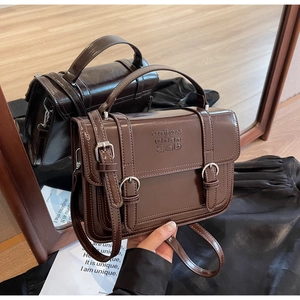 Detail of vintage brown leather handbag with embossed letters and adjustable strap