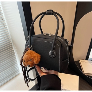 Detail of black Boston bag featuring white contrast stitching and a plush teddy charm