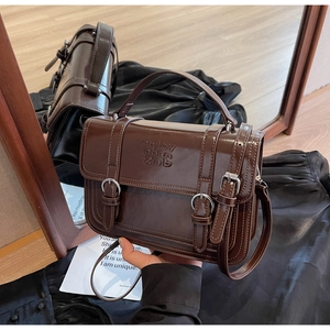 Detail of dark brown glossy leather handbag with double buckles and embossed logo