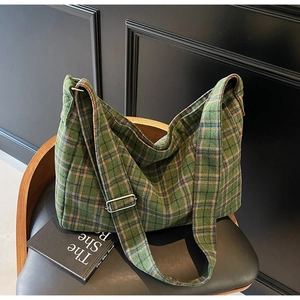 Close-up of green plaid tote bag with woven texture and adjustable strap on a chair