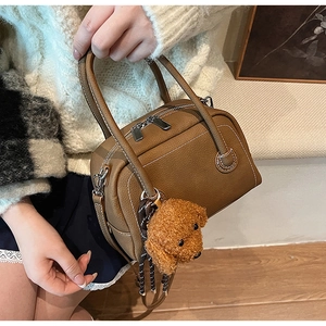 Detail of brown litchi pattern leather bowling bag with cute teddy dog charm on side