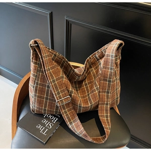 Detailed close-up of brown plaid tote bag with thick wool texture and adjustable strap