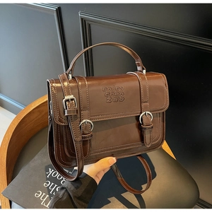 Close-up of retro dark brown leather handbag with embossed letters and metal buckles