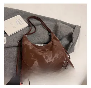 Detailed close-up of brown crescent hobo bag with unique lace-up side knots on grey wool