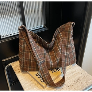 Macro shot of brown plaid hobo bag with adjustable wide strap on marble surface