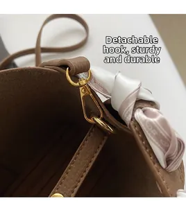 Detail of brown litchi pattern leather bucket bag with gold metal ring and floral scarf