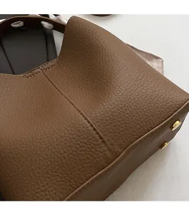 Detail of brown litchi pattern leather bucket bag with metal feet and decorative scarf