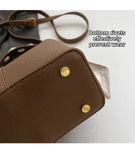 Close-up of brown pebbled leather bucket bag bottom with gold protective metal studs