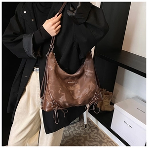 Detail of vintage dark brown tote bag featuring side lace-up design and metallic logo tag