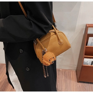 Detail of vintage lychee grain Boston bag with cute teddy pendant on a model