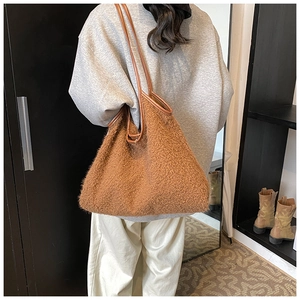 Λεπτομέρεια καφέ tote τσάντας από γούνα teddy με δερμάτινα λουριά σε μοντέλο