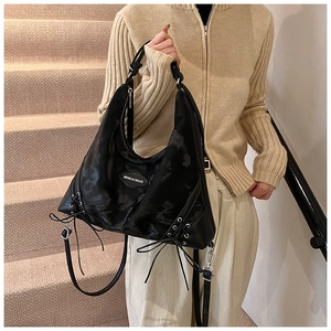 Detail of black large capacity tote bag featuring side lace-up design and silver hardware