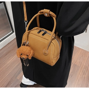 Brown lychee leather bowling bag with twin handles and cute poodle plush charm detail