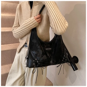 Detail of black glossy tote bag featuring decorative side lacing and marbled texture