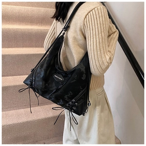 Detail of black glossy tote bag with cross drawstring accents and silver metal zipper