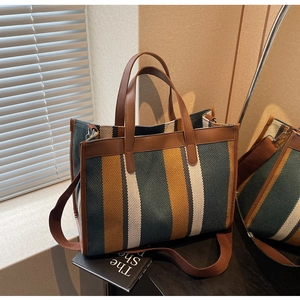Detail of color-block striped tote bag with leather handles and natural shadow lighting