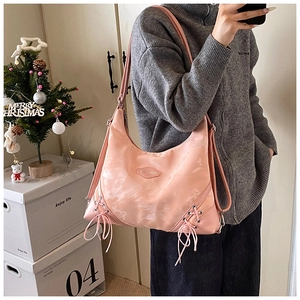 Detail of pink nylon tote bag featuring decorative ribbon bows and wide shoulder strap
