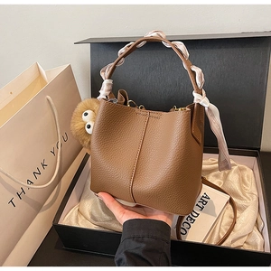 Brown bucket bag with silk scarf handle and plush charm in a luxury gift box