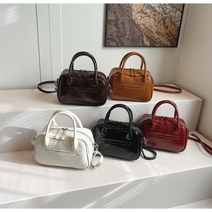 Detailed arrangement of shiny Boston bags in five colors with top handles and shoulder straps