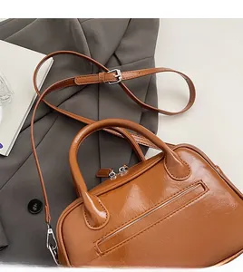 Detail of brown leather handbag featuring adjustable shoulder strap and smooth zip closure
