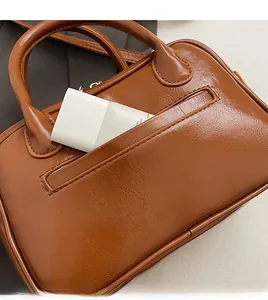 Detail view of the brown shoulder bag front pocket for cosmetic storage organization