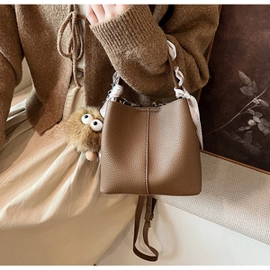 Detail of brown litchi leather bucket bag with printed silk scarf and plush charm