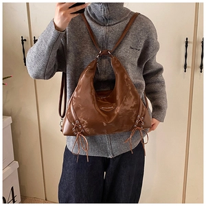 Detail of brown crescent tote bag with silver eyelets and side lace-up design