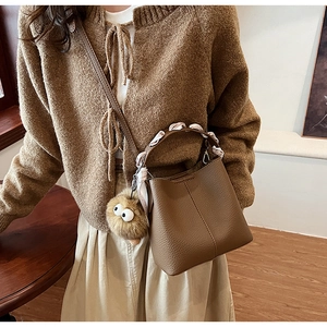 Brown lychee leather bucket bag with silk scarf handle and plush eye charm detail