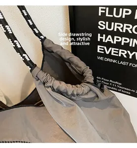 Detail view of the functional side drawstring and woven geometric shoulder strap of grey tote